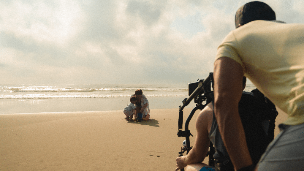 Travel video production team filming people on a beach at a tourist destination