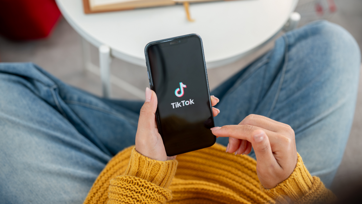 The TikTok logo on a phone in a woman's hand