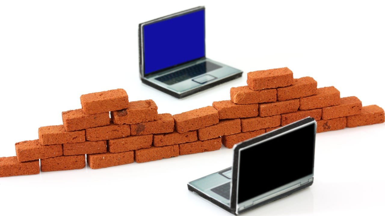 brick wall being built to separate two laptops